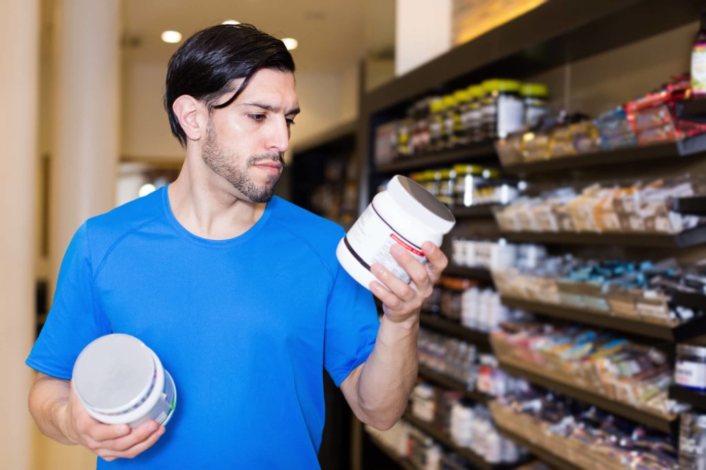 A shopper comparing supplements in a supplement store.