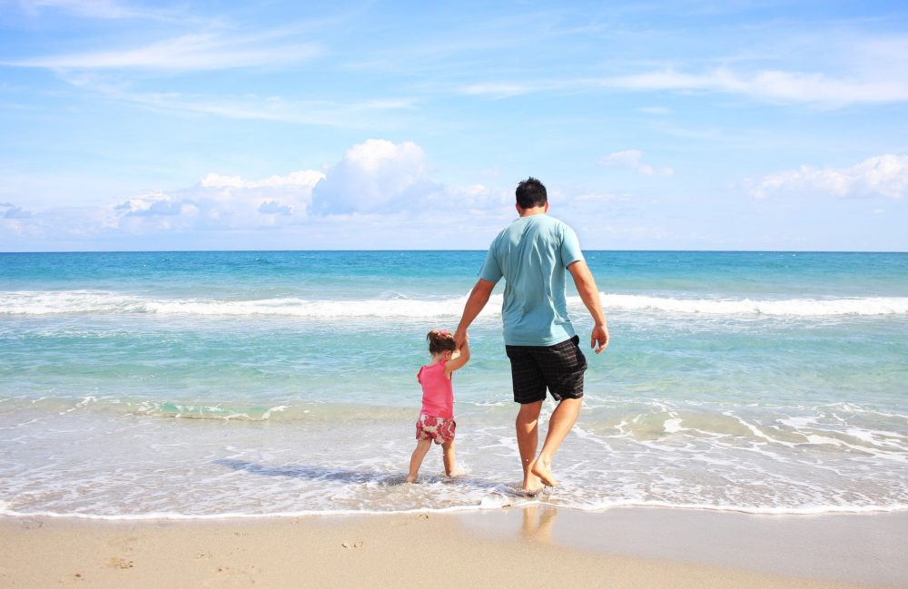 A picture of a father and daughter walking on the beach